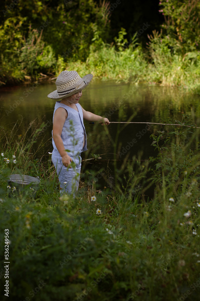 Boy fisherman, catches fish on the river bank in summer Boy fisherman, catches fish on the river bank in summer