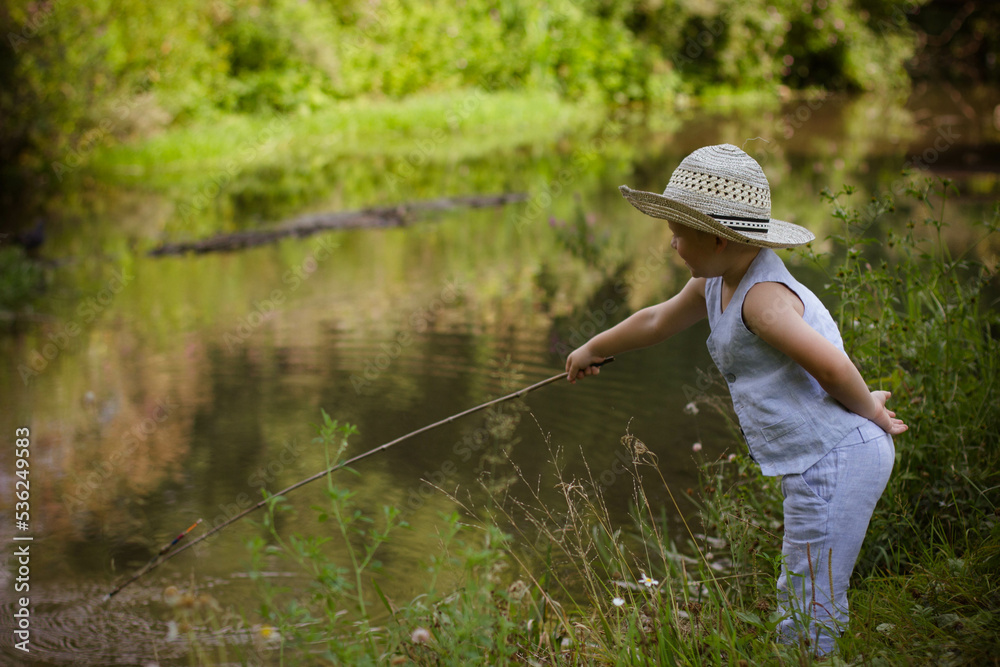 Boy fisherman, catches fish on the river bank in summer Boy fisherman, catches fish on the river bank in summer