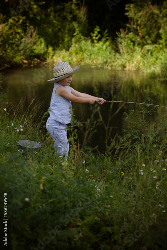 Boy fisherman, catches fish on the river bank in summer