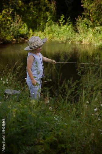 Boy fisherman, catches fish on the river bank in summer