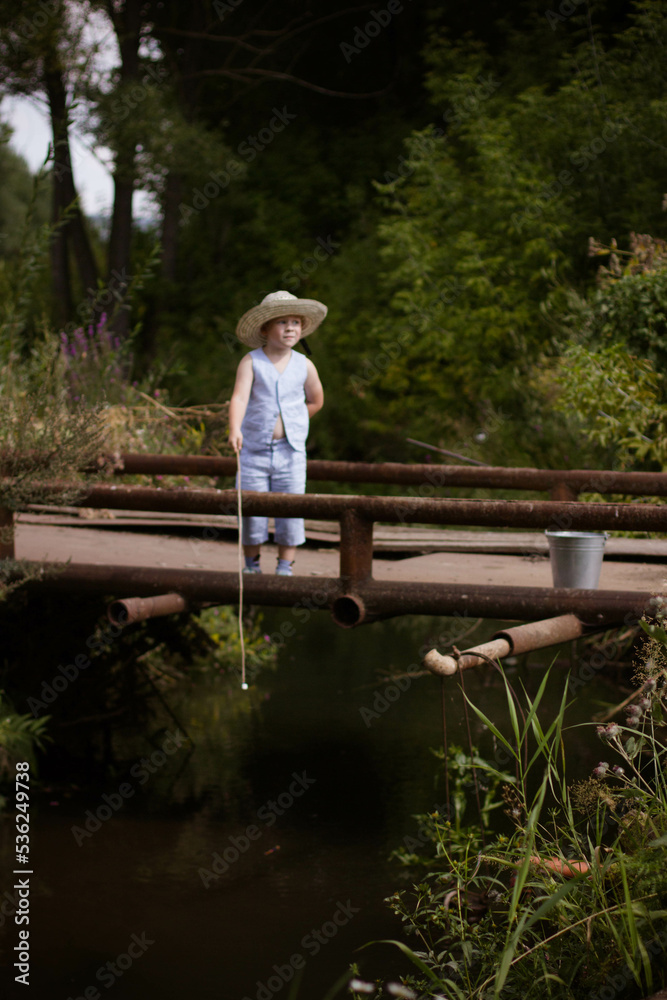 Boy fisherman, catches fish on the river bank in summer Boy fisherman, catches fish on the river bank in summer
