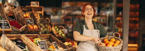 Successful grocery store owner holding a basket of fresh organic fruits