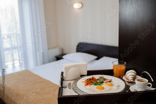 Tasty fresh breakfast with scrambled eggs and vegetables in bed at the hotel room