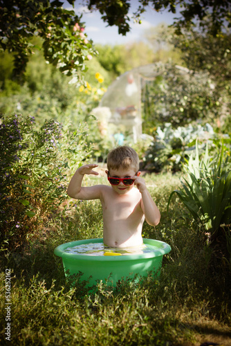 boy playing in a bowl of water in the garden