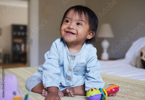 Photo Down Syndrome, smile and happy baby relax on bed having fun, play with toys and enjoy happiness at home