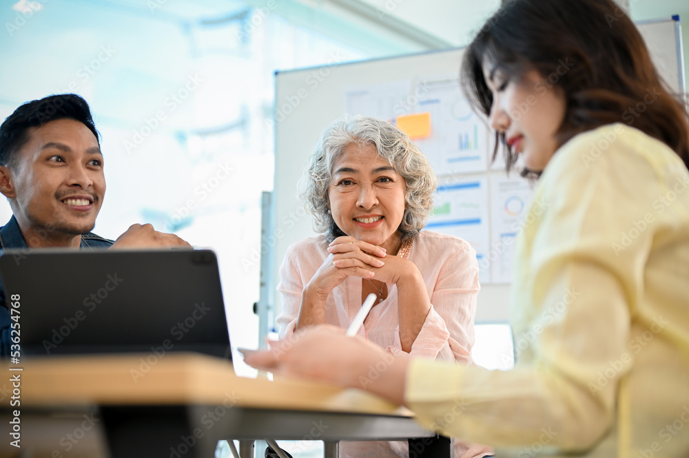 Successful-aged Asian female boss in the meeting with her marketing team. Successful-aged Asian female boss in the meeting with her marketing team.