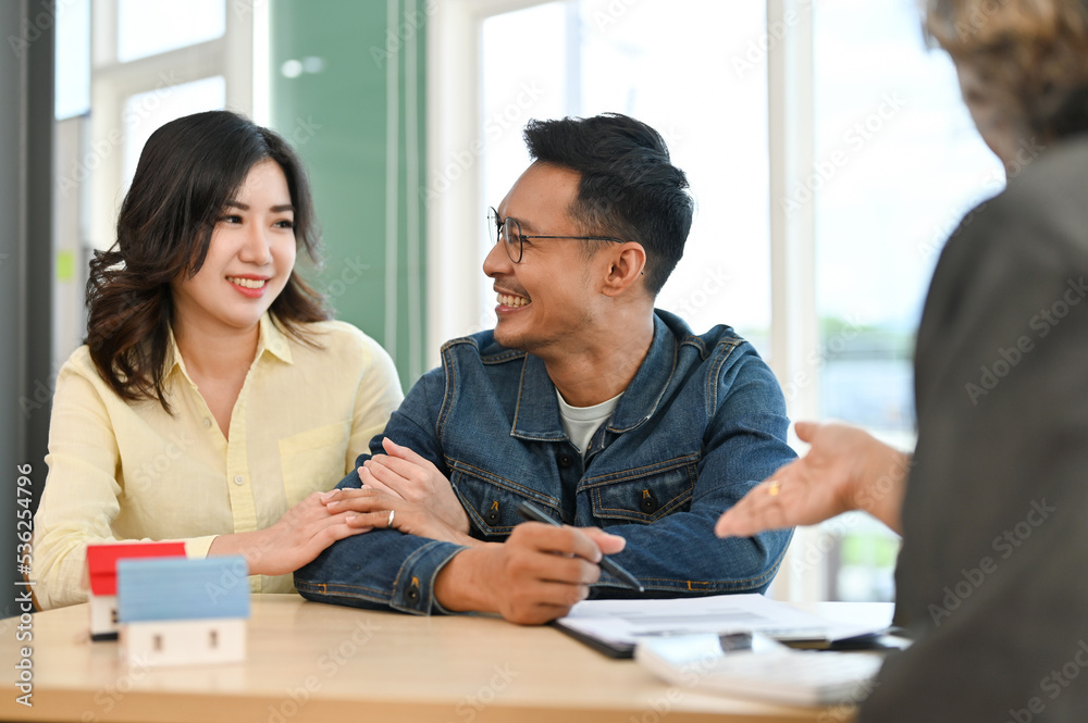 Fototapeta premium Lovely Asian couple meeting with their real estate agent to sign a lease and pay a security deposit