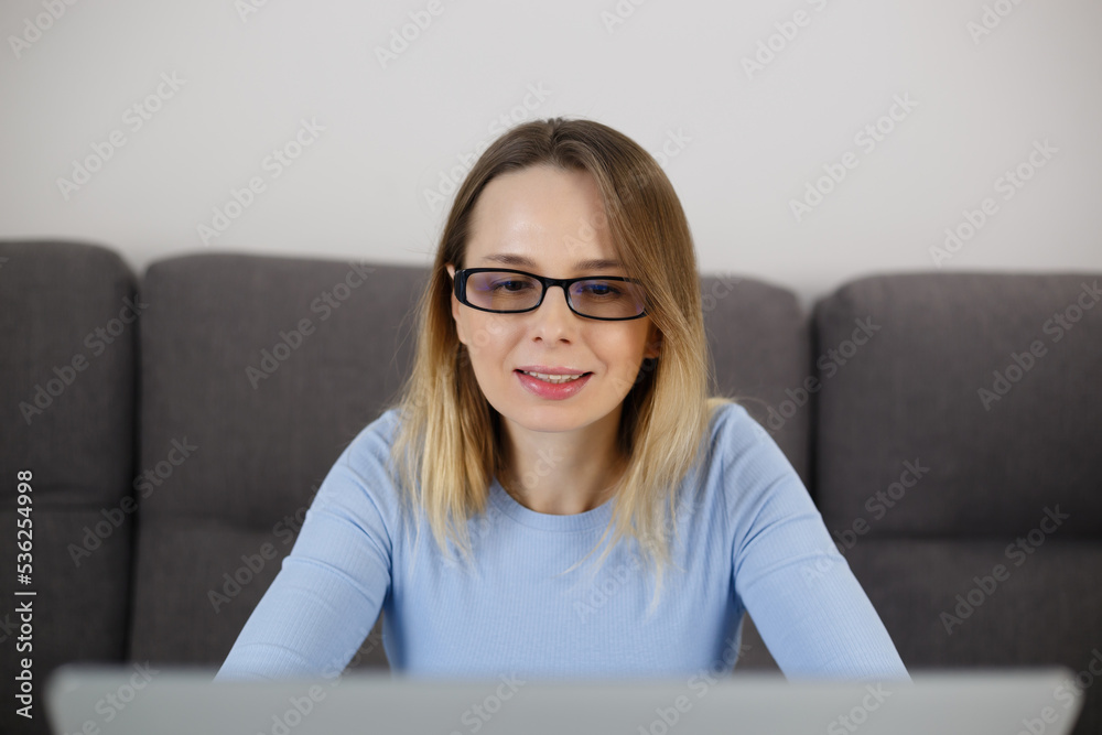 White woman working on notebook computer at home. Portrait of adult female person reading text on laptop screen White woman working on notebook computer at home. Portrait of adult female person reading text on laptop screen