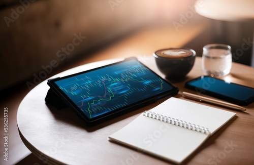 Tablet computer with chart on screen with note book, coffee cup, mobile phone on wooden table, Business concept people take a break during a day and working or trading stocks