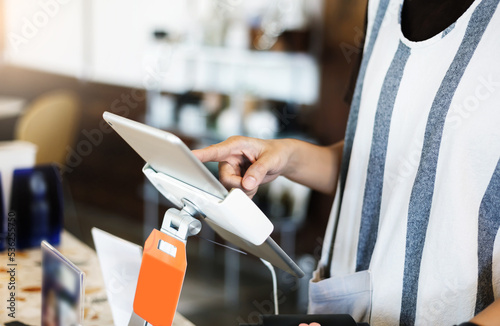 Close-up view,  young asian woman  touching on the digital tablet to recive order from customer in coffee shop. Concept small business or new business photo