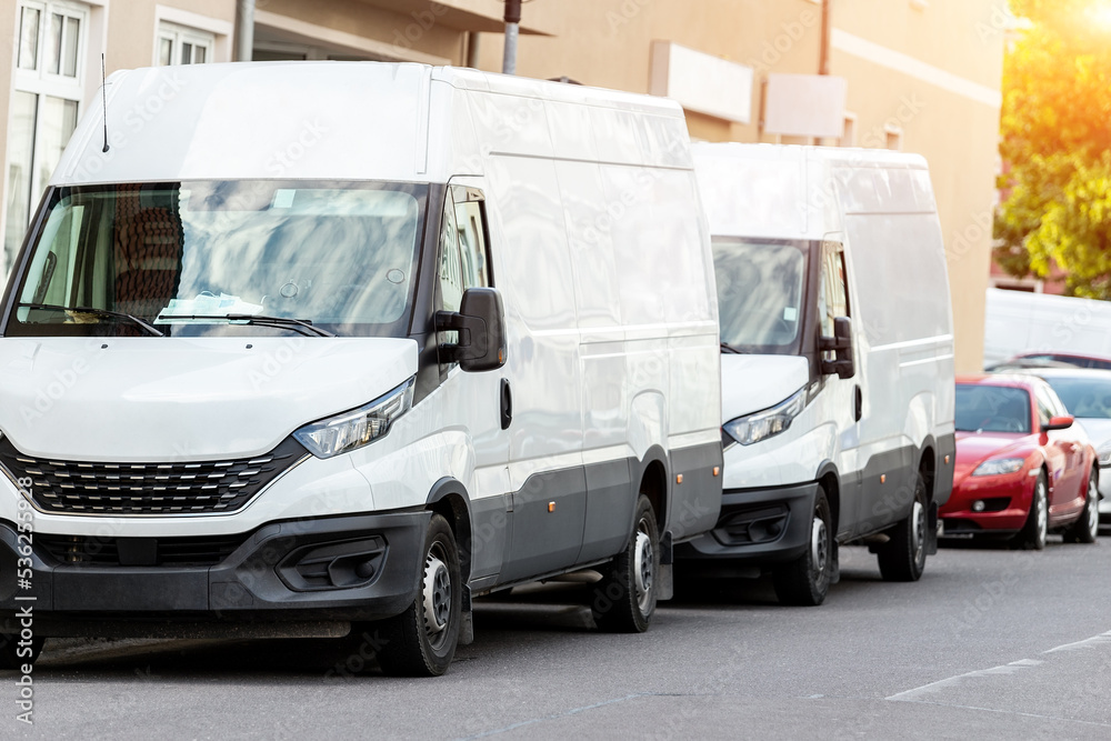 Small cargo delivery van parked in european city central district. Medium lorry minivan courier vehicle deliver package at residential office building in downtown area. Commercial shipping logistics
