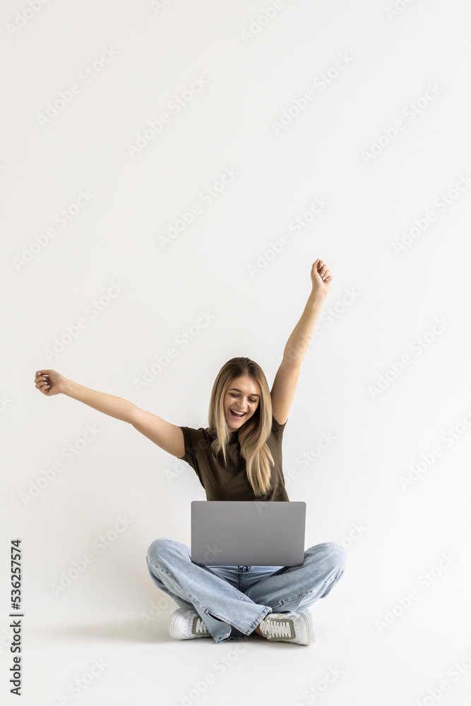 Young woman sitting with laptop with win gesture on white background Young woman sitting with laptop with win gesture on white background