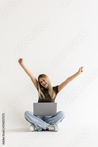 Young woman sitting with laptop with win gesture on white background © dianagrytsku