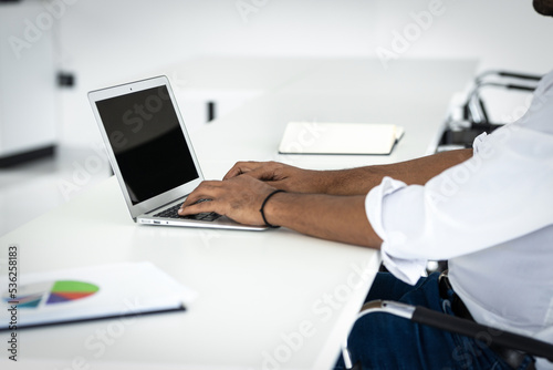 Portrait of a young afro american businessman, doing serious work in his office. Futuritstic scenes Business man doing paperwork using laptop and mobile phone