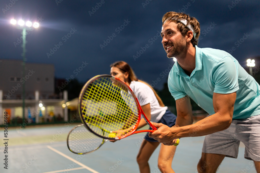 Tennis sport people concept. Mixed doubles player hitting tennis ball with partner standing near net