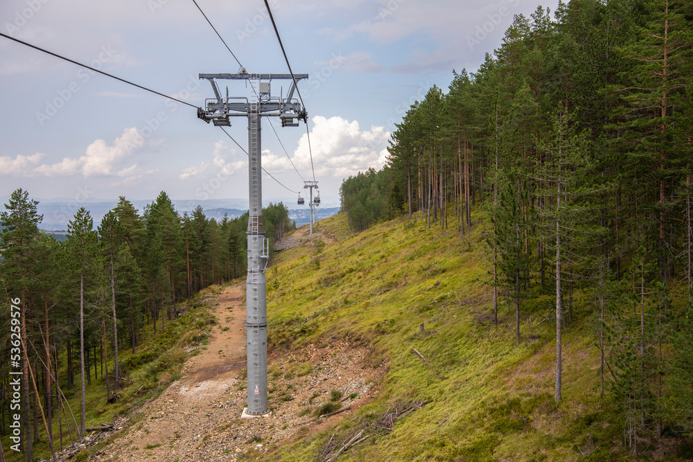 Tourists sit in big suspended glass cabins riding to mountain peak. Scenic nature view. Cable car gold gondola lift is providing an aerial link over mountain Zlatibor in Serbia. 07.09.2022 Tourists sit in big suspended glass cabins riding to mountain peak. Scenic nature view. Cable car gold gondola lift is providing an aerial link over mountain Zlatibor in Serbia. 07.09.2022