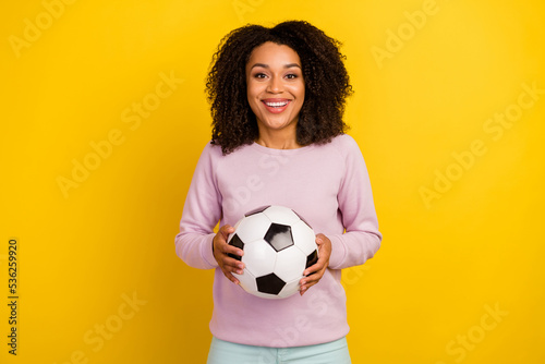 Photo of young lovely lady hold soccer ball match play free-time isolated over yellow color background © Tetiana