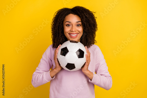 Photo of young girl good mood play football match sportive competition goal isolated over yellow color background © Tetiana