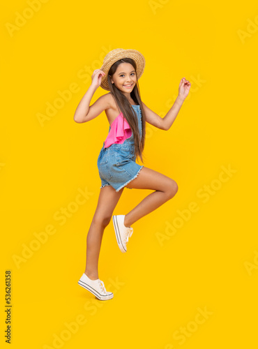Fototapeta Naklejka Na Ścianę i Meble -  happy teen girl in straw hat running on yellow background