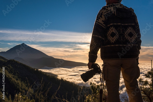 Photography modern digital remote work and travel lifestyle - man from back view and beautiful valley and mountains in background - modern people traveler and remote worker - camera dslr adult