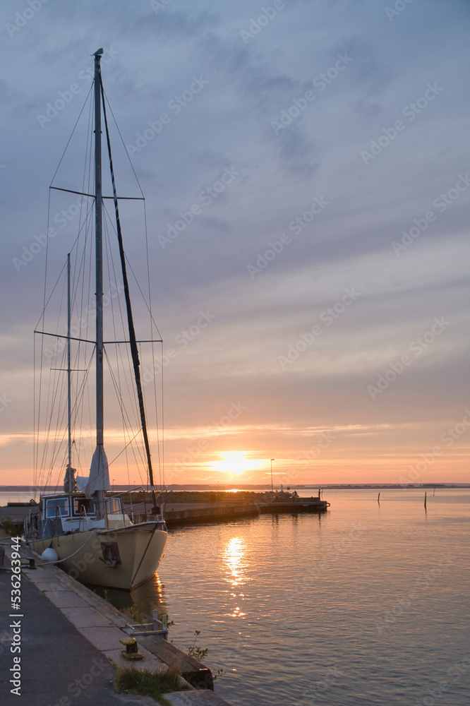 Sailing ship in the harbor of lake Vaettern at sunset. Lighthouse in the background Sailing ship in the harbor of lake Vaettern at sunset. Lighthouse in the background
