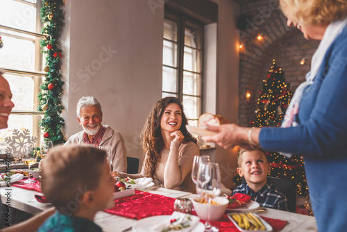 Senior woman placing food on the table for family Christmas dinner