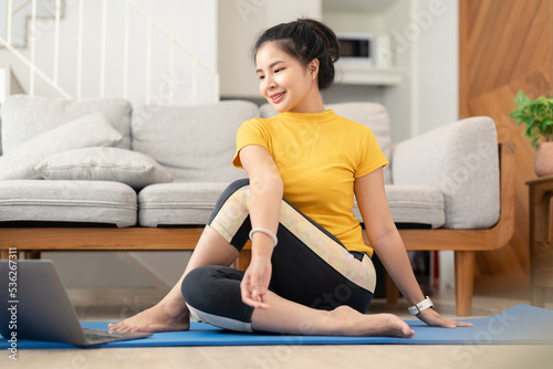 Attractive young woman doing yoga stretching yoga online at home. Self-isolation is beneficial. Healthy lifestyle concept