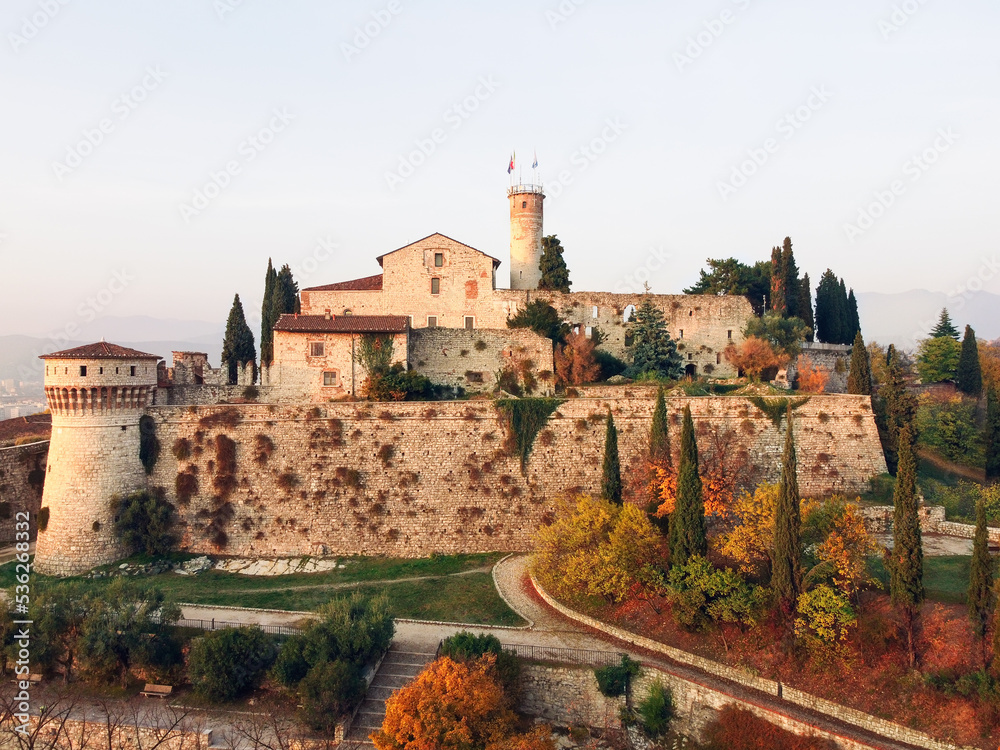 Maxi panoramic drone view on ancient medieval castle in Brescia on top of Cidneon mountain enframed by autumn park. Brescia, Lombardy, Northern Italy Maxi panoramic drone view on ancient medieval castle in Brescia on top of Cidneon mountain enframed by autumn park. Brescia, Lombardy, Northern Italy