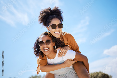 Summer, friends and freedom with women and piggy back against the blue sky for hug, lifestyle and happy on Puerto rico holiday. Youth, crazy and friend with girl on vacation with glasses and a smile
