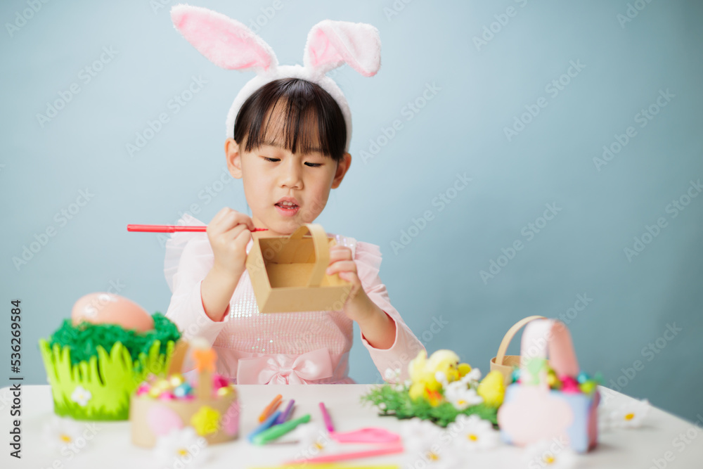 young girl making easter craft against plain background young girl making easter craft against plain background