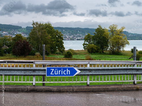 Au ZH, Switzerland - September 15.2022: Directional traffic sign for Zurich, Switzerland with a view of lake Zurich
