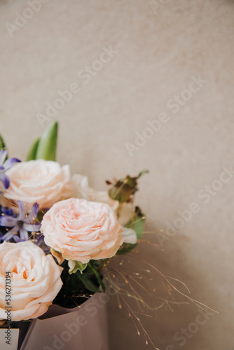 A bouquet of flowers  roses  dahlias  gladioli in a beautiful pink package on a light stone background. Front view