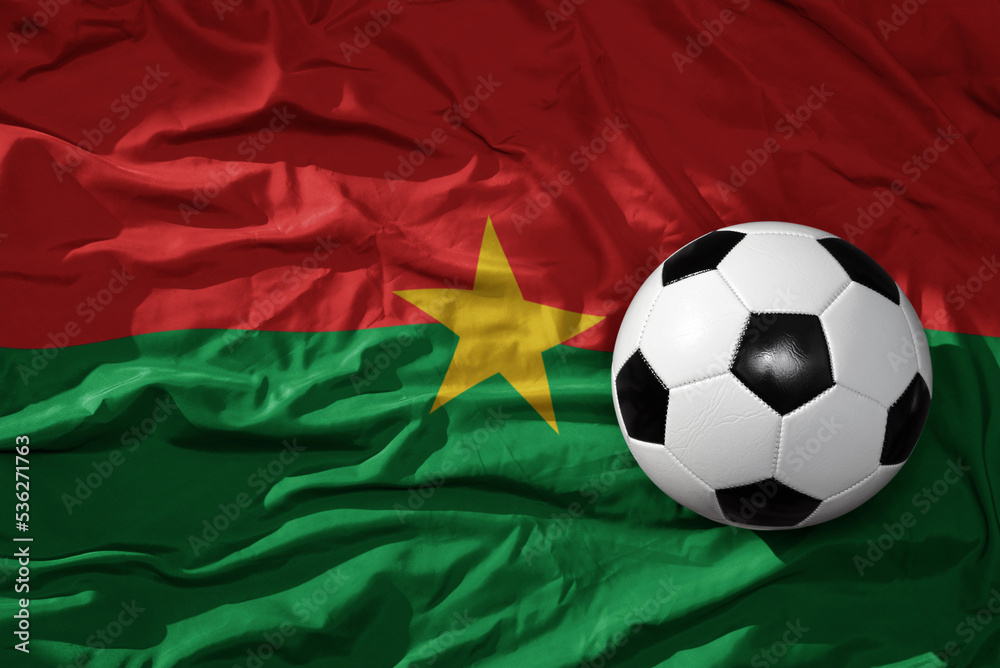 Naklejka premium vintage football ball on the waveing national flag of burkina faso background. 3D illustration