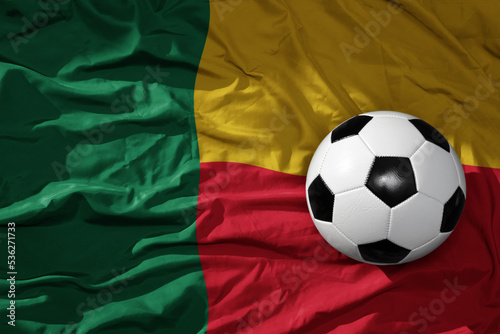 vintage football ball on the waveing national flag of benin background. 3D illustration