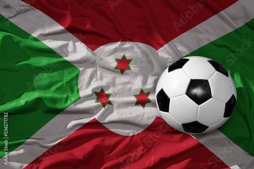vintage football ball on the waveing national flag of burundi background. 3D illustration