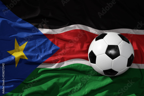 vintage football ball on the waveing national flag of south sudan background. 3D illustration