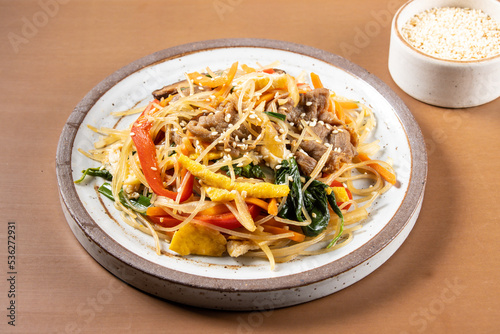 Japchae is Korean traditional dish, stir-fried Korean vermicelli noodles with vegetables and slices beeef, topping with sesame seeds.