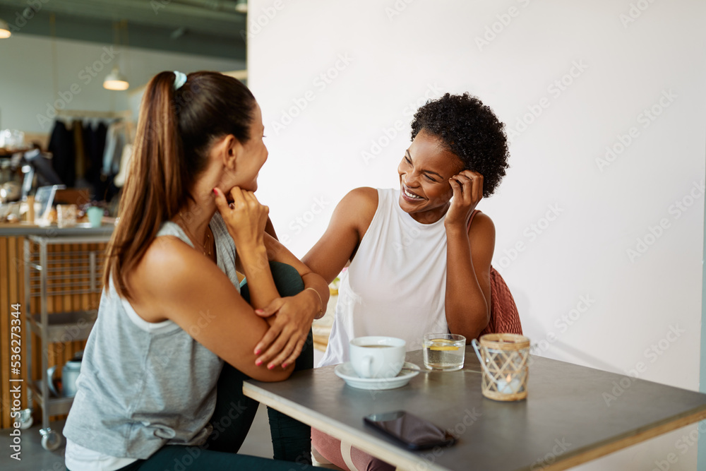 Smiling friends in sportswear talking over coffee after a workout Smiling friends in sportswear talking over coffee after a workout