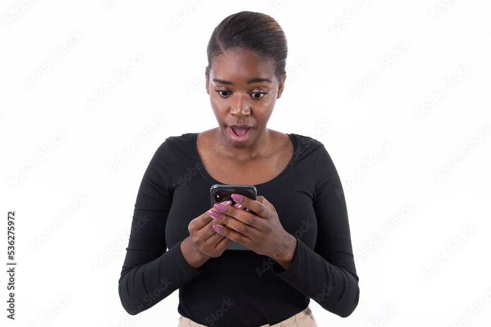 Portrait of excited young woman reading newsletter on smartphone. African American lady wearing black long sleeve looking at mobile phone in surprise against white background.Mobile technology concept Portrait of excited young woman reading newsletter on smartphone. African American lady wearing black long sleeve looking at mobile phone in surprise against white background.Mobile technology concept