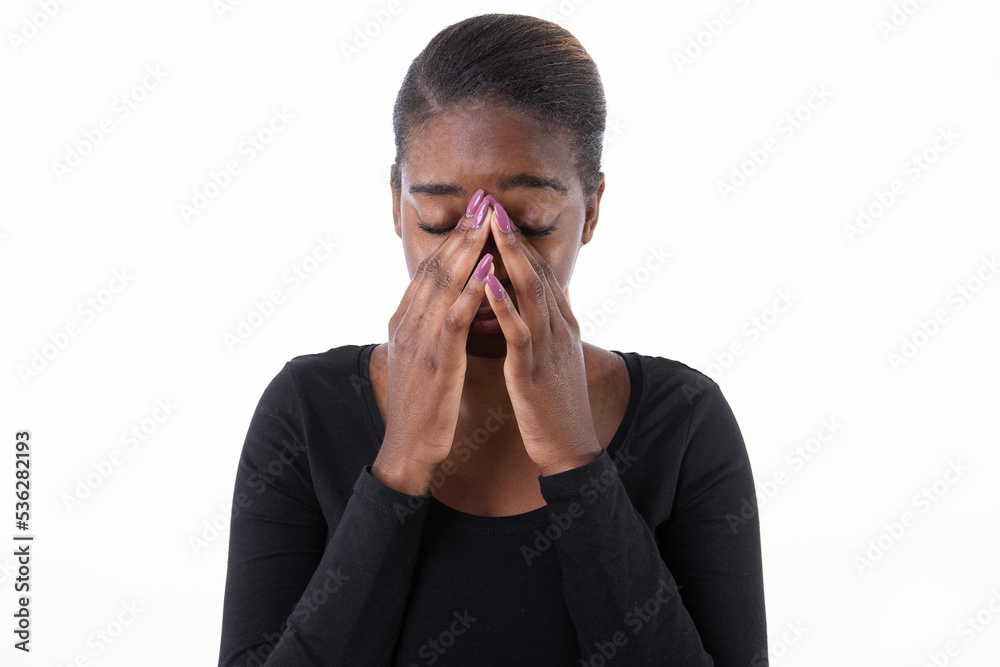 Portrait of tired African American woman with headache. Sick young model in black shirt with ponytail massaging bridge of nose, eyes closed. Headache, overwork concept. Portrait of tired African American woman with headache. Sick young model in black shirt with ponytail massaging bridge of nose, eyes closed. Headache, overwork concept.