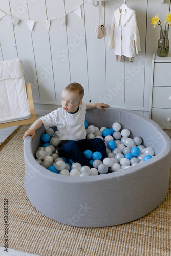 Child plays in a children's pool with plastic balls. Concept of active pastime