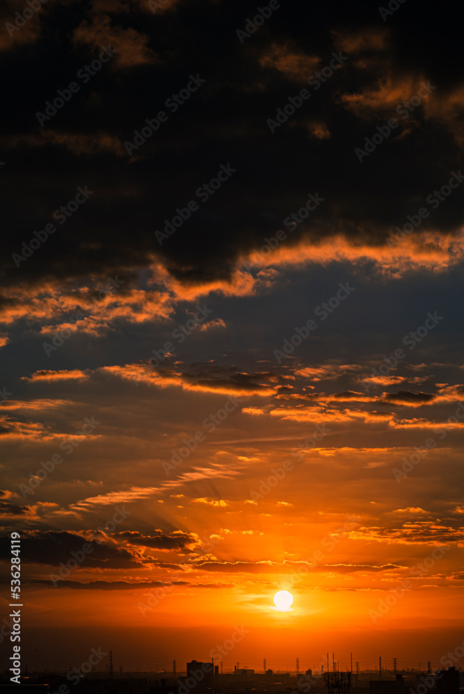 夕陽に染まる雲と遠くに浮かぶ鉄塔