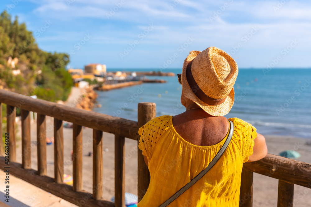 Elderly lady looking at the sea beach of La Caleta in Cabo Roig. Alicante. senior travel