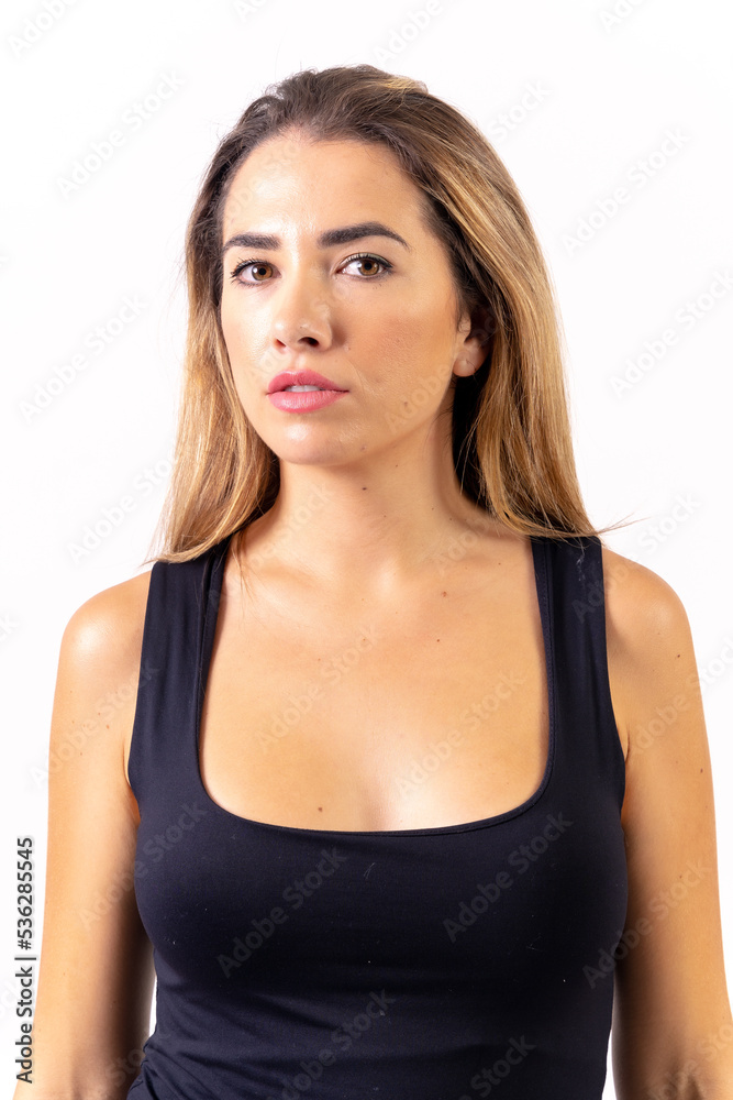 Portrait of a blonde woman in a black tank top on a white background, serious looking at the camera Portrait of a blonde woman in a black tank top on a white background, serious looking at the camera