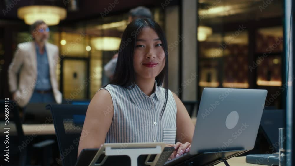 Asian businesswoman looking at the camera while working on business strategy in modern office using laptop and digital tablet. E-commerce company Asian businesswoman looking at the camera while working on business strategy in modern office using laptop and digital tablet. E-commerce company