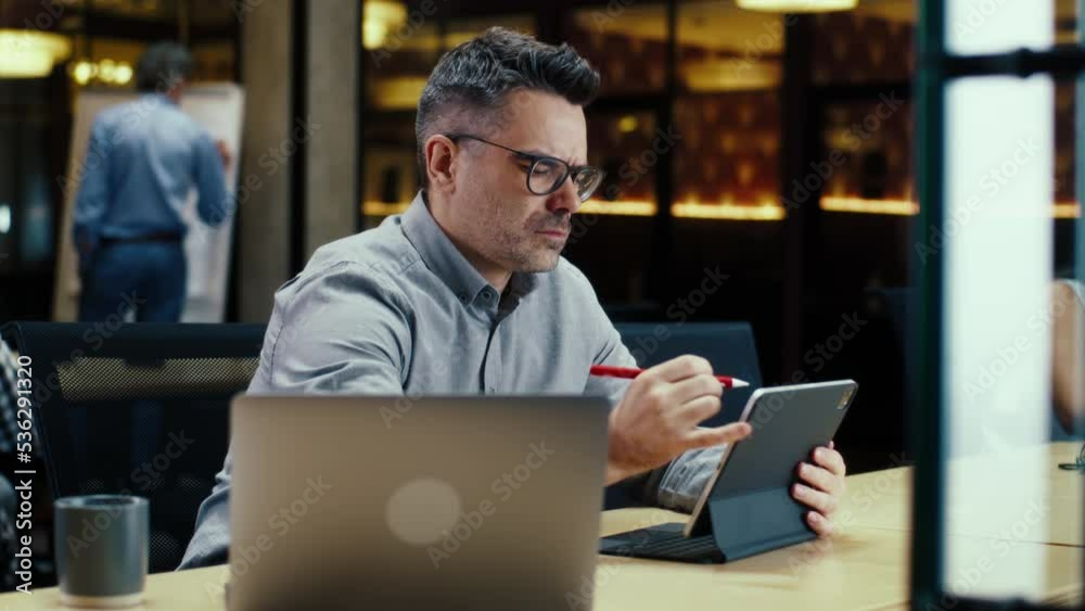 Male office worker, using tablet computer and digital pencil, working in modern office on startup project, business strategy or design of website. Work in IT company Male office worker, using tablet computer and digital pencil, working in modern office on startup project, business strategy or design of website. Work in IT company