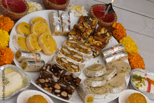 Mix indian sweets like kaju roll dryfruits barfi mango peda served in a plate photo