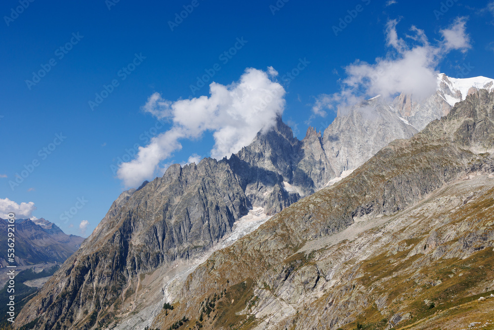 Mountain Range of the Italian Alps on a Sunny Summer Day, close-up view of the Rocks  and Blue Sky with Clouds