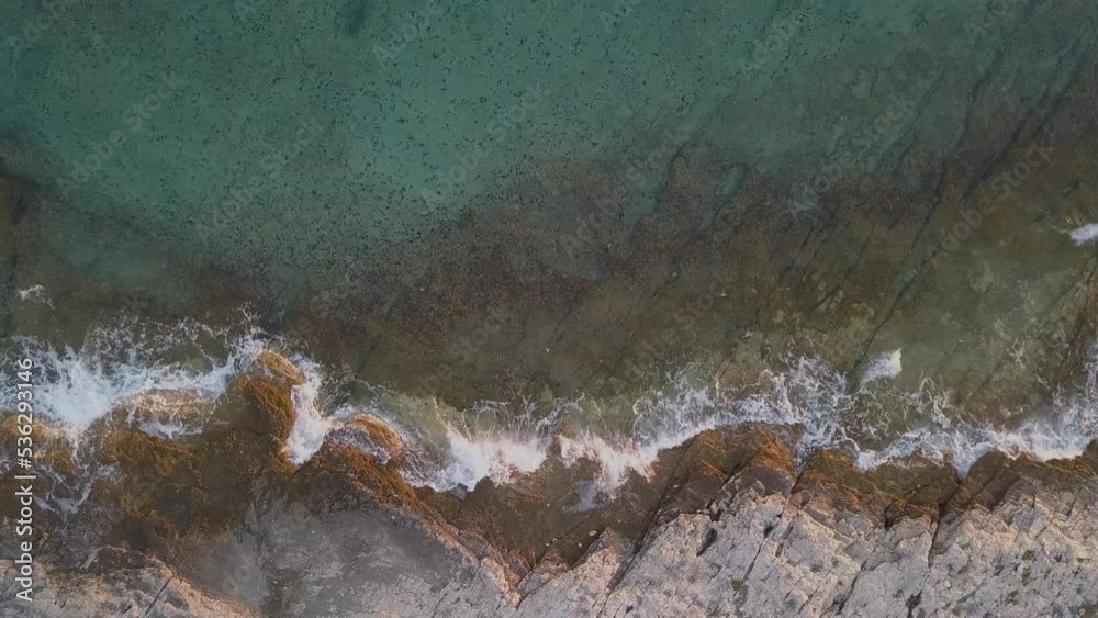 Aerial drone view of sea and rocks on the beach. Beautiful natural rocky beach at summer. Waves crushing on wild beach at sunset. Coastline. Transparent sea water Aerial drone view of sea and rocks on the beach. Beautiful natural rocky beach at summer. Waves crushing on wild beach at sunset. Coastline. Transparent sea water