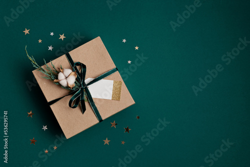 Christmas background with gift box wrapped in kraft paper. Xmas celebration, preparation for winter holidays. Festive mockup, top view, flat lay in natural colos photo
